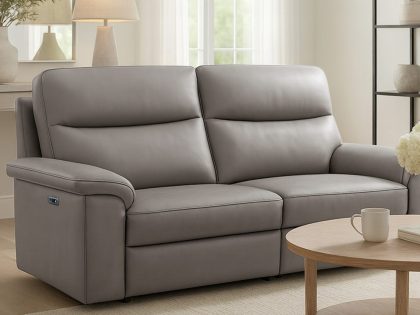 A contemporary grey two‑seater recliner sofa is shown in a light, minimalist living room with neutral décor and a round wooden coffee table.